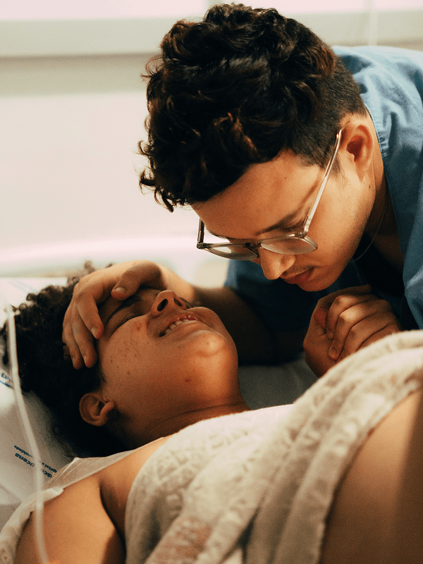 A family member sitting quietly beside a hospital bed, holding their relative's hand